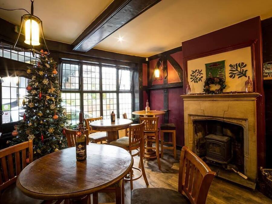 A cozy pub with wooden furniture, a Christmas tree, and a fireplace.