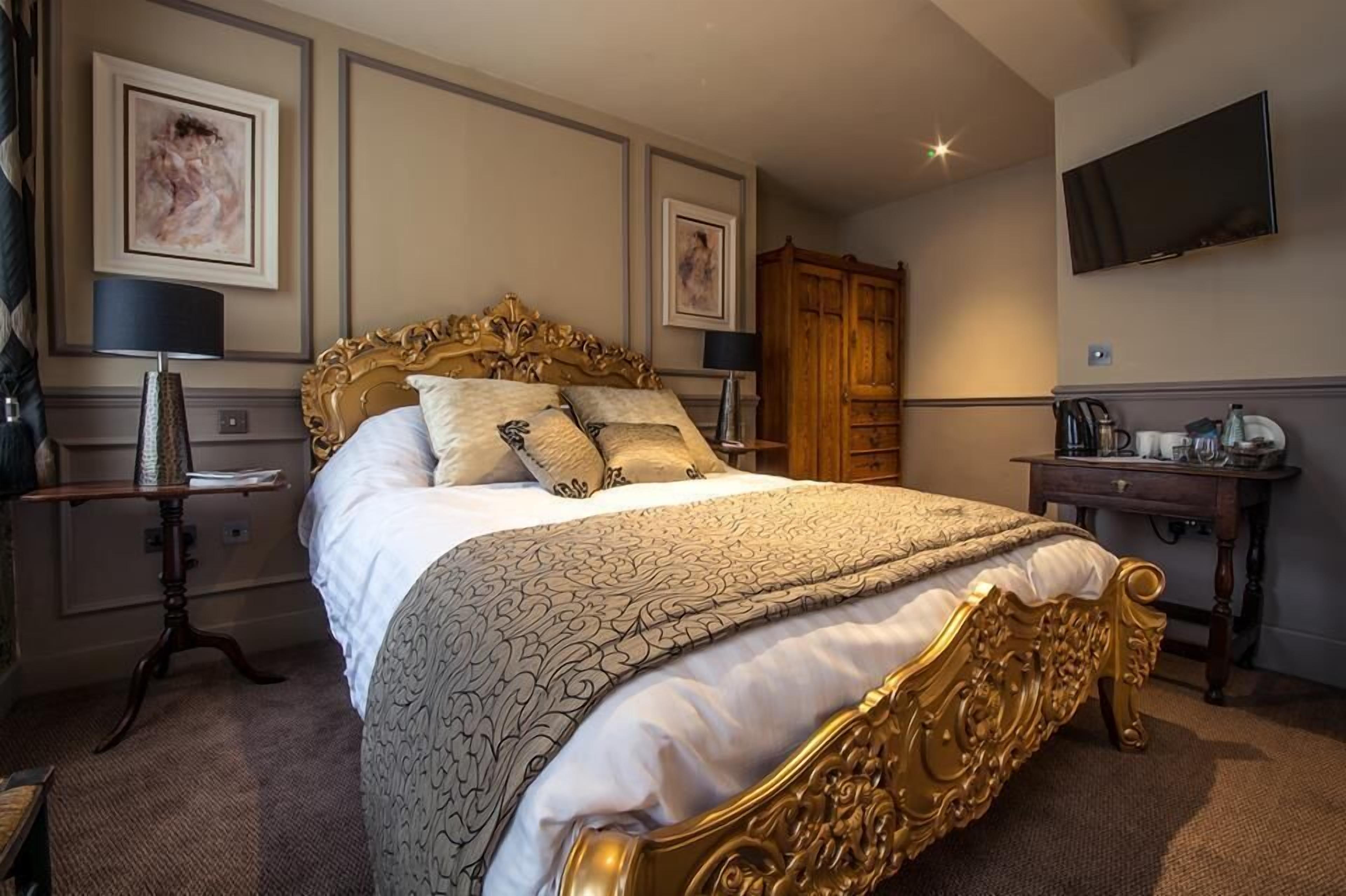 A well-appointed hotel room with a large bed, a television, a desk with a lamp, and a wardrobe.