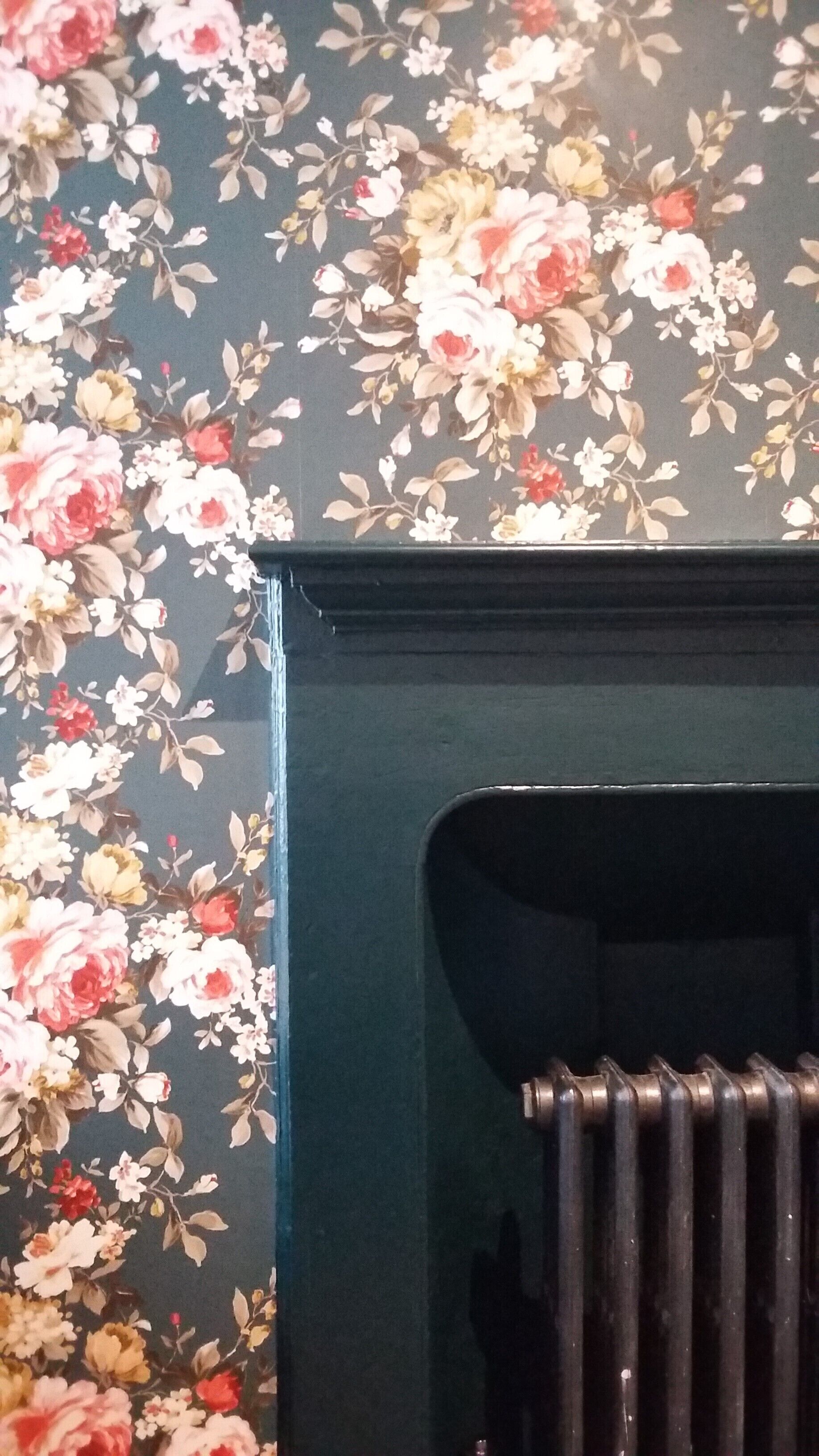A radiator in a room with floral wallpaper.