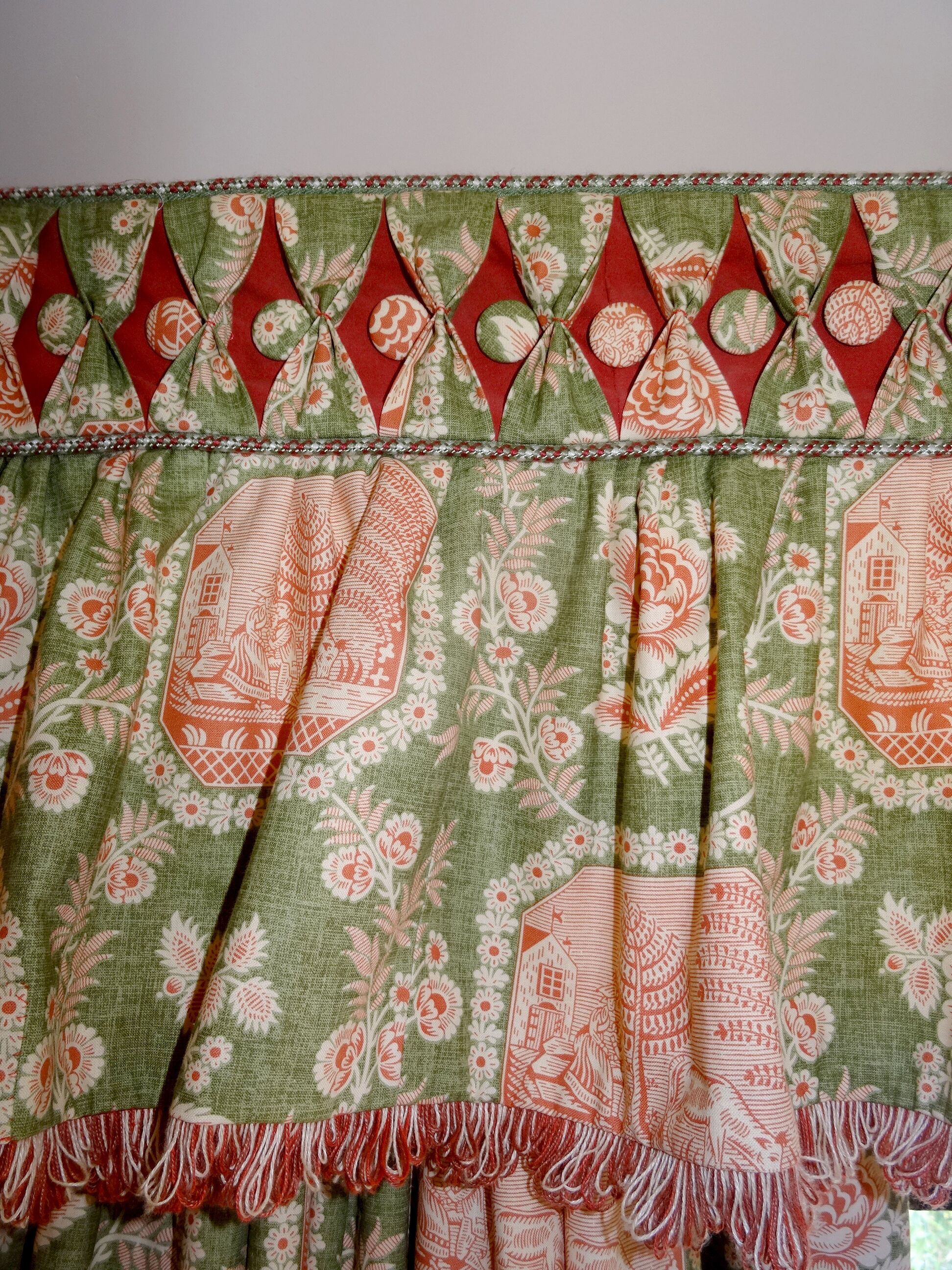 A green and red patterned fabric with a fringe at the bottom.