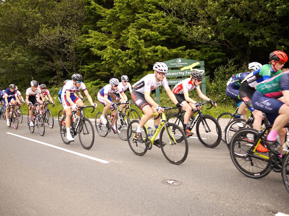 A group of cyclists on a road with trees in the background.