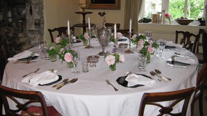 A round dining table set for a meal with white tablecloth, candles, and floral centerpieces. - Hollamoor Farm B&B (Barnstaple)