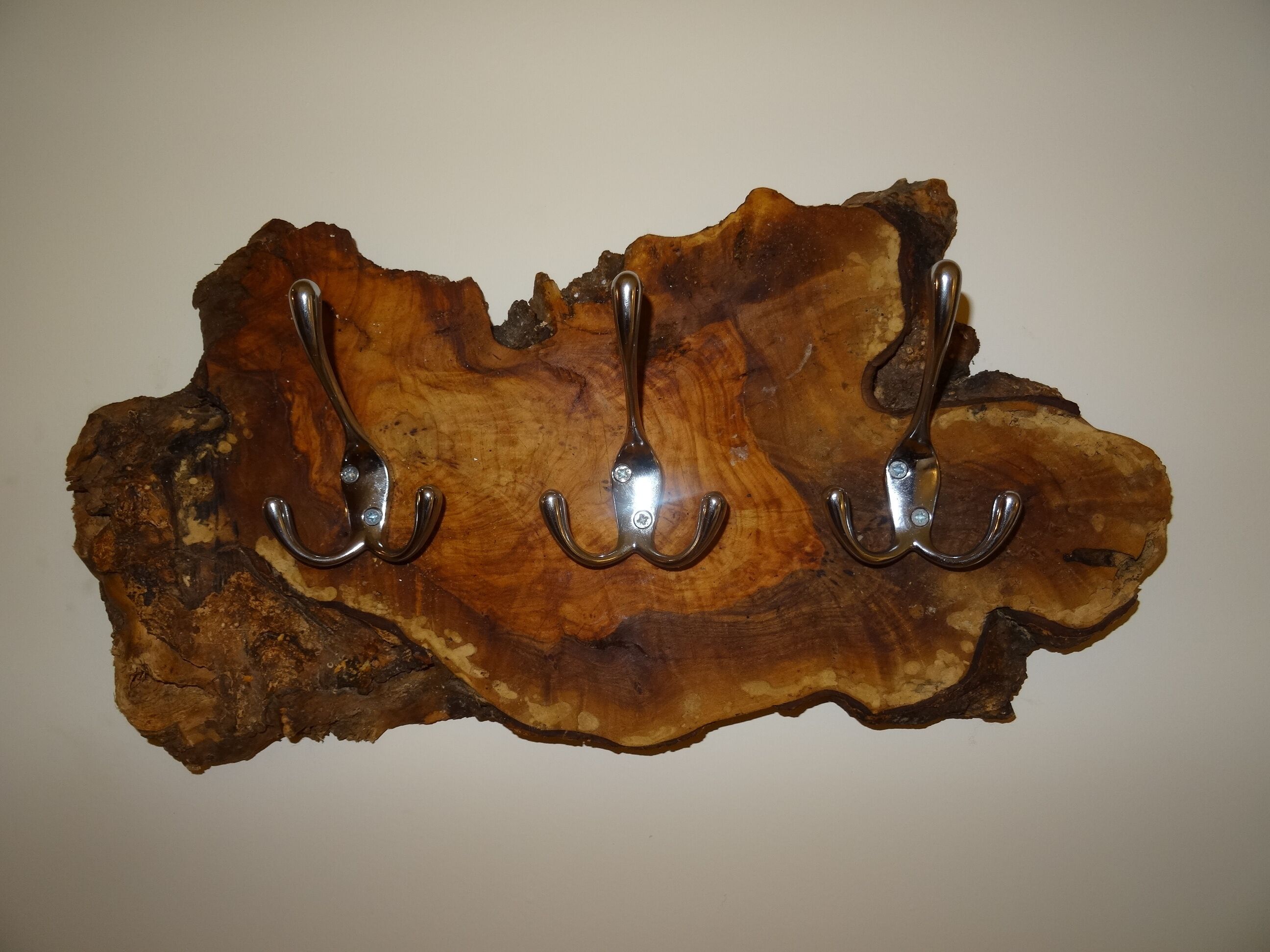 A wooden surface with three metal hooks.