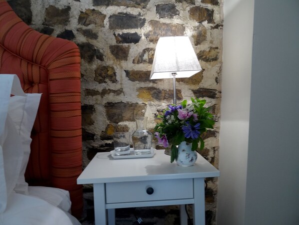 A white bedside table with a lamp, a vase with flowers, and a glass of water. - Hollamoor Farm B&B (Barnstaple)