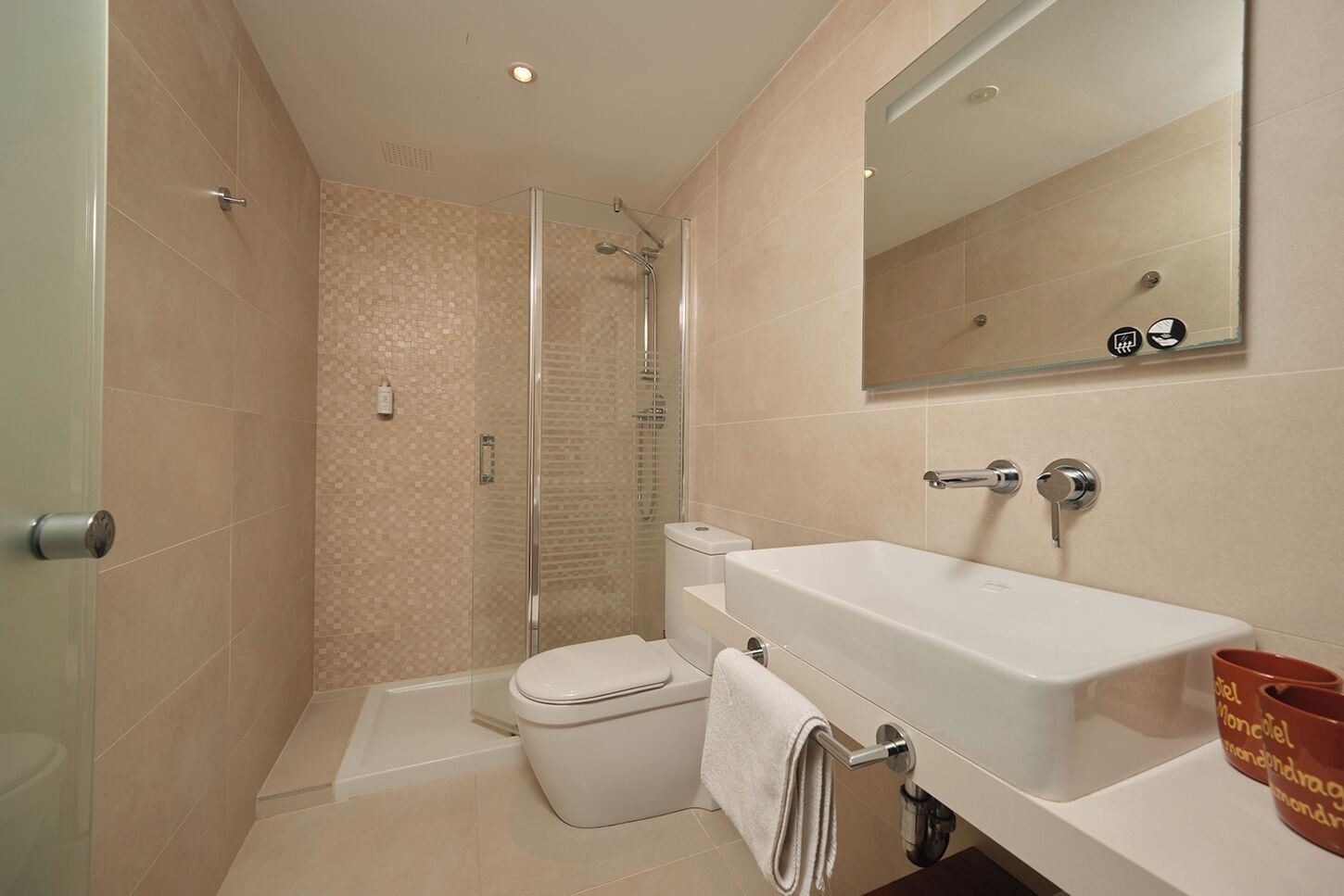 A modern bathroom with a glass-enclosed shower, a white sink, and a toilet.