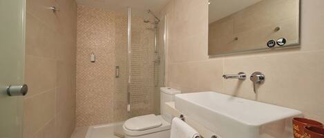 A modern bathroom with a glass-enclosed shower, a white sink, and a toilet.