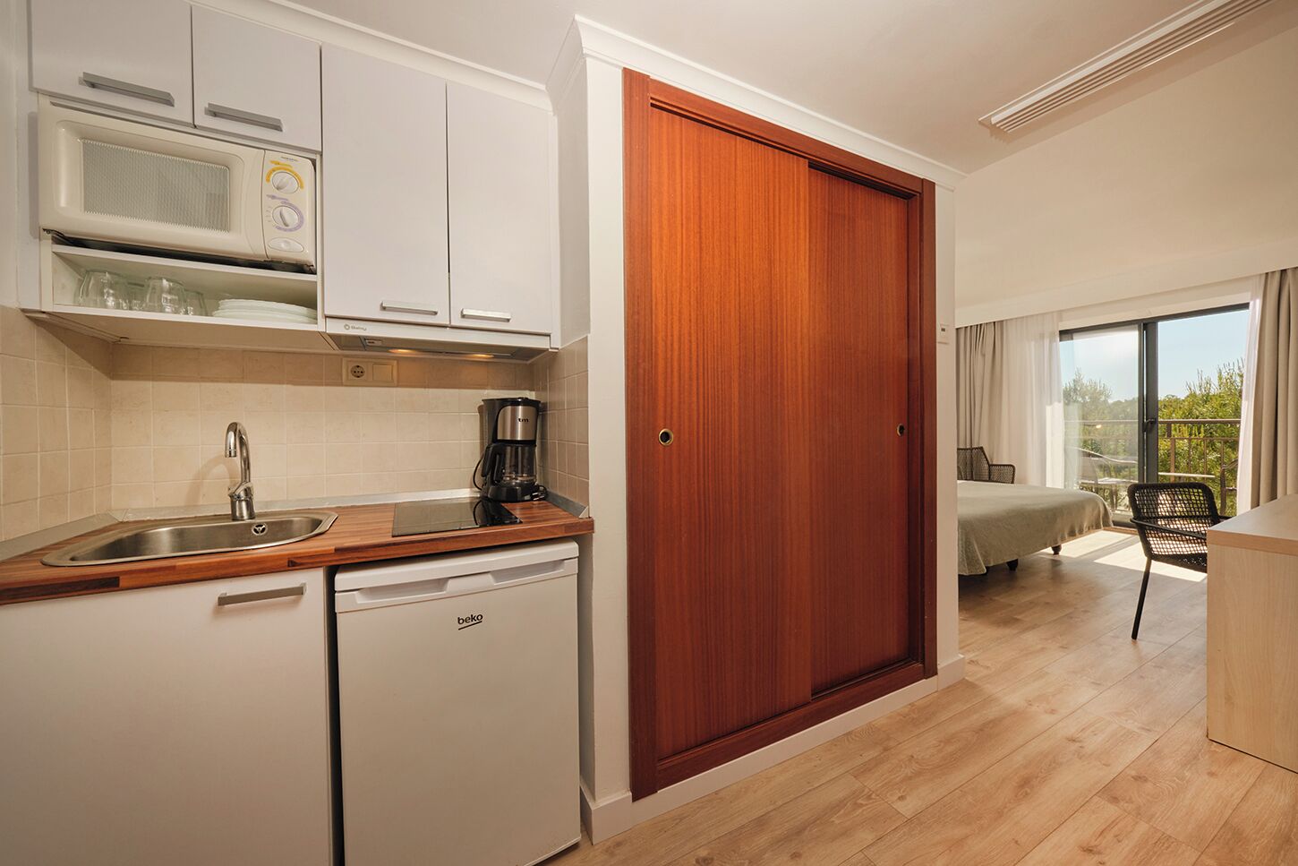 A compact kitchen with a dishwasher, a coffee maker, and a microwave.