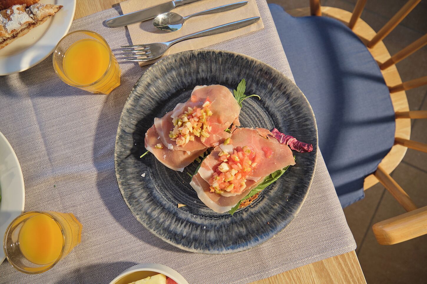Une assiette remplie de nourriture, un verre de jus de fruits et des couverts sur une table.