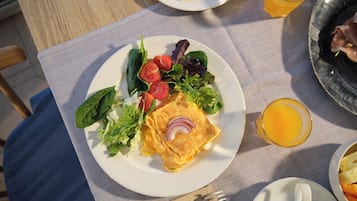 A breakfast plate with eggs, tomatoes, lettuce, and a glass of orange juice on a table.