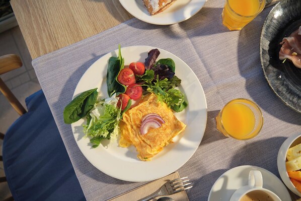 A breakfast plate with eggs, tomatoes, lettuce, and a glass of orange juice on a table. - Hotel Playa Mondrago (Santanyi)