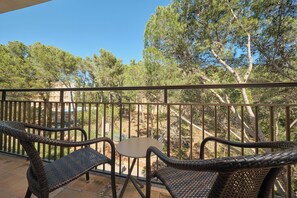 A balcony with wicker furniture and a view of trees. - Hotel Playa Mondrago (Santanyi)