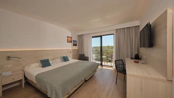 Una habitación de hotel moderna con una cama grande, un escritorio, una silla, un televisor y un balcón con vistas.