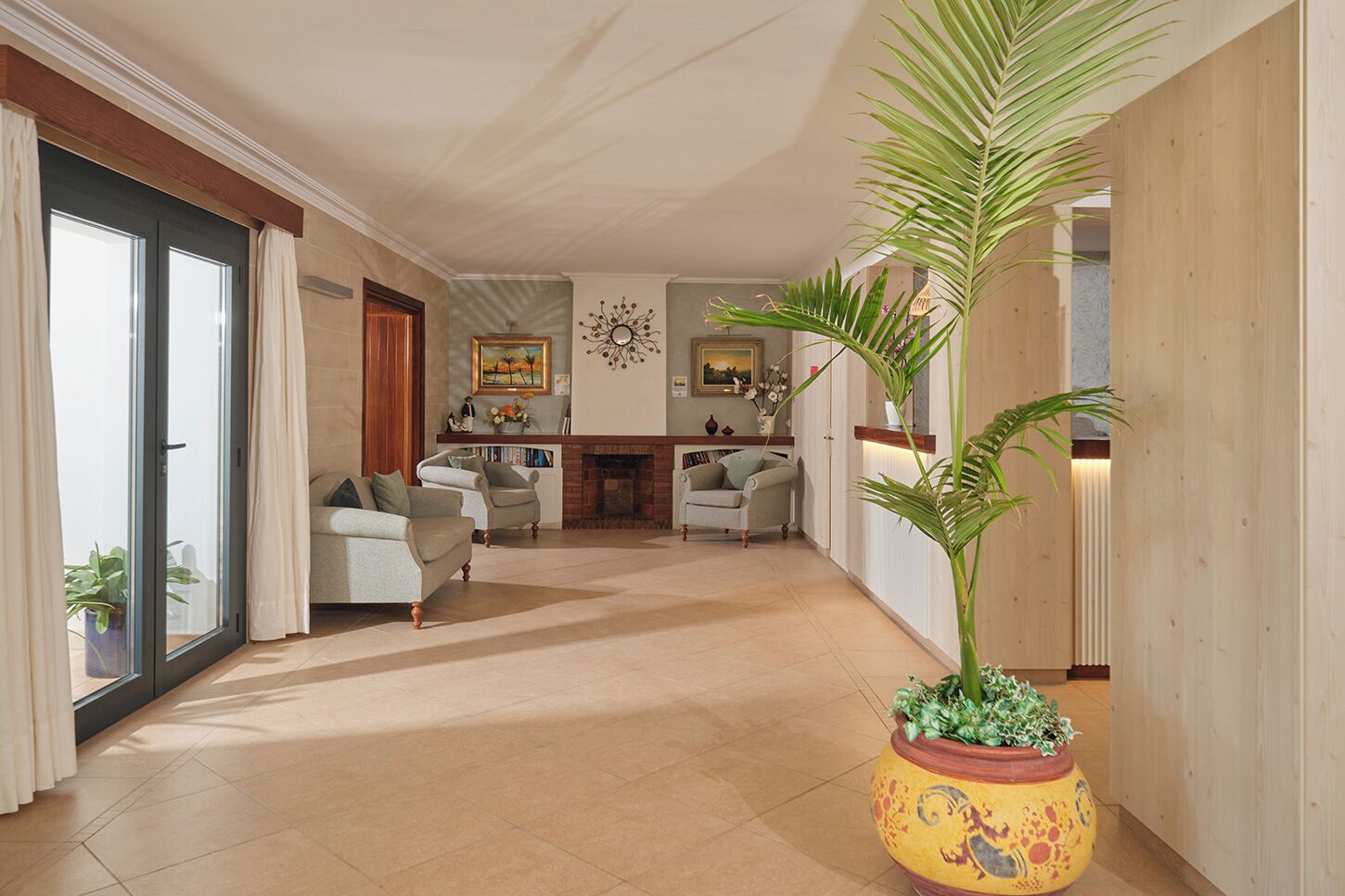 A spacious living area with a fireplace, two sofas, a coffee table, and a large potted plant.
