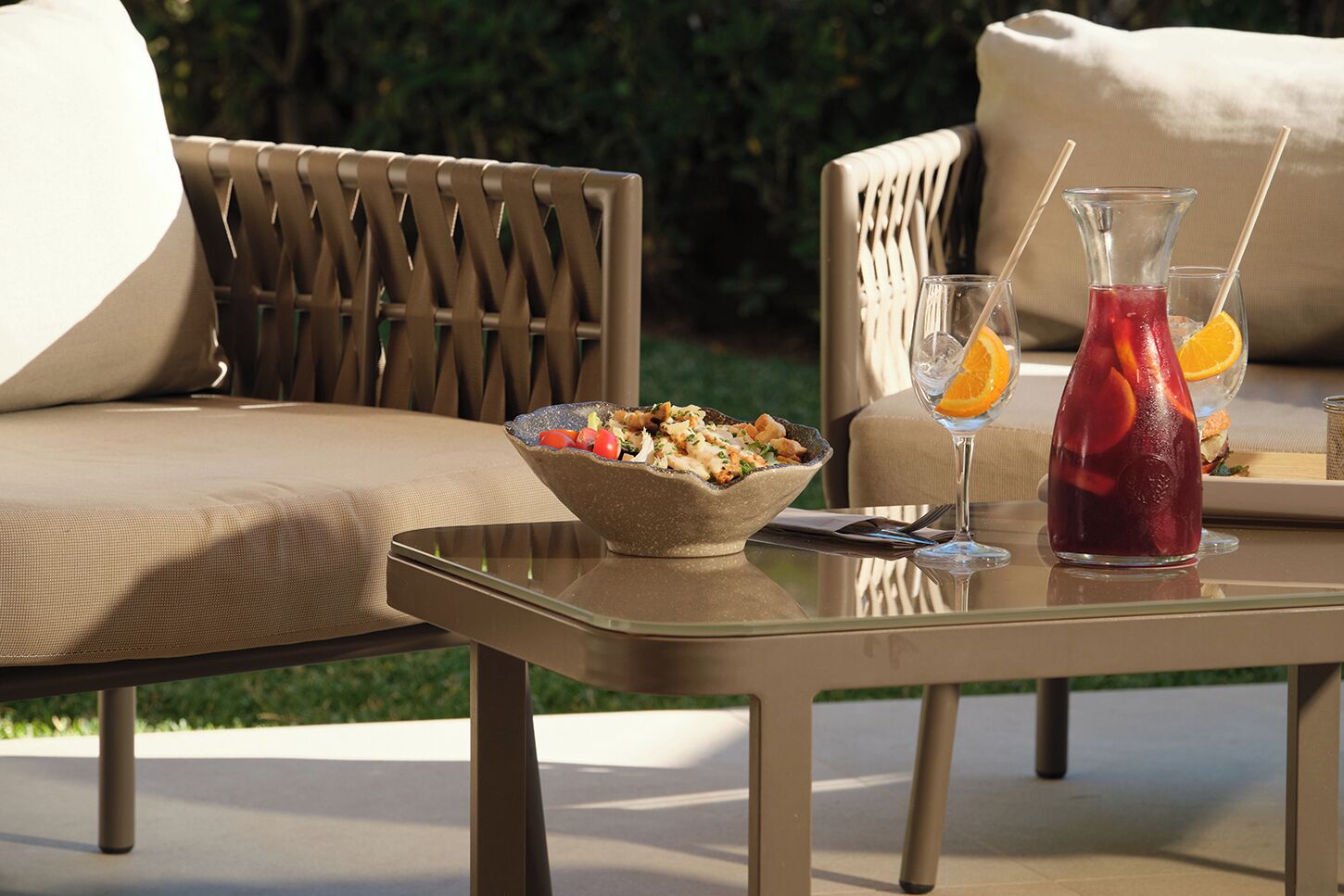 Un área de comedor al aire libre con una mesa, sillas, un bol de comida y una bebida con fruta.