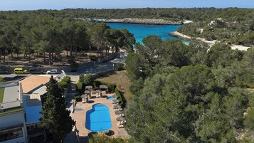 Una piscina al aire libre, sombrillas, sillones reclinables de piscina