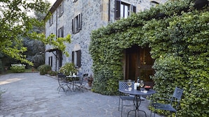 An outdoor patio with stone flooring, tables, and chairs.