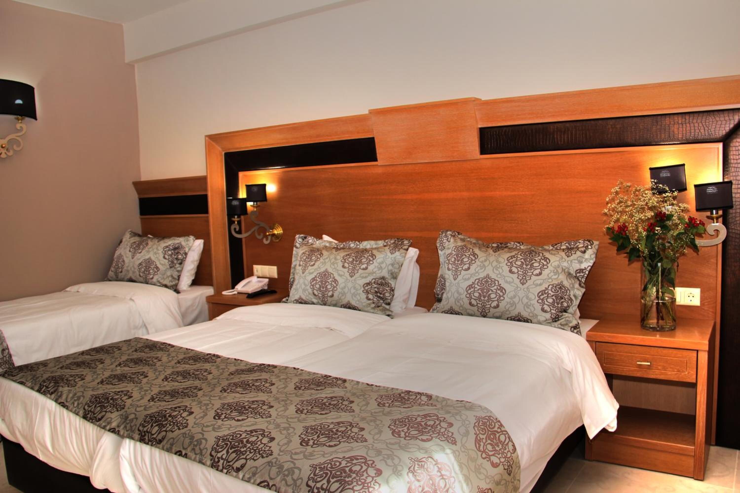 Une chambre d’hôtel avec un grand lit, deux tables de chevet, une petite table et une lampe fixée au mur.
