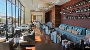 A spacious indoor area with a long row of tables and chairs, a large sofa, and a wall decorated with multiple hanging lanterns. - Lancaster Plaza Beirut (Beirut)