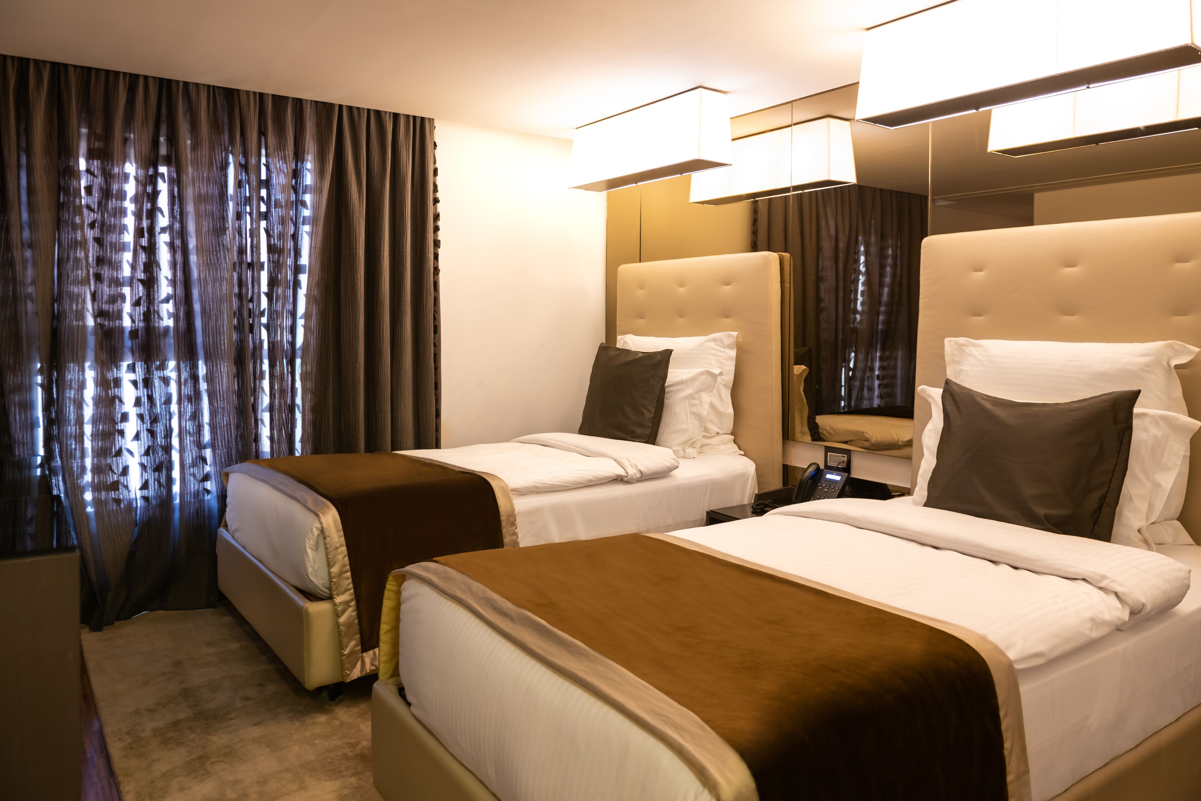 A hotel room with two beds, a large mirror, and a carpeted floor.