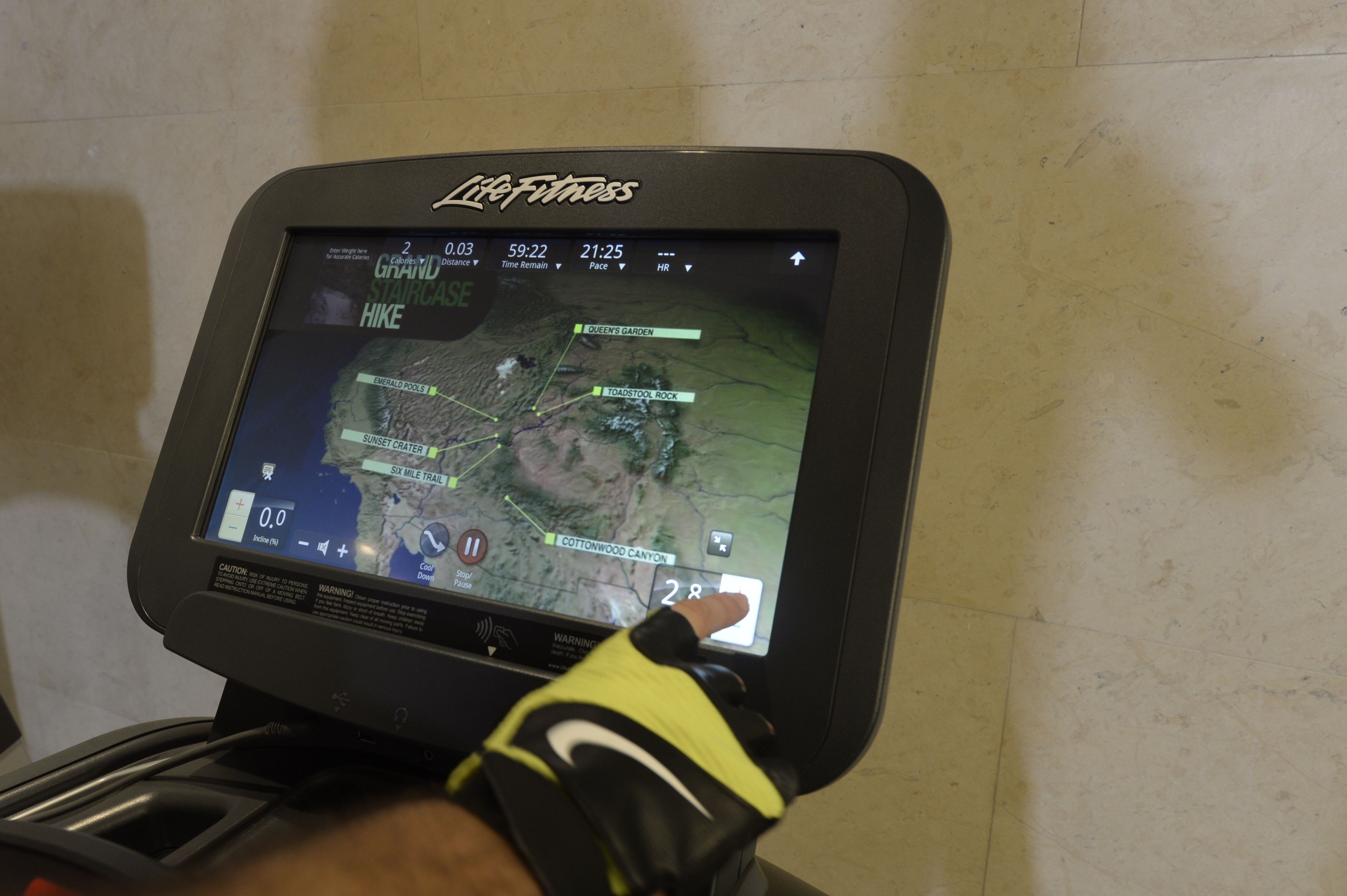 Una bicicleta estática Life Fitness con una pantalla digital que muestra un mapa y datos del entrenamiento.