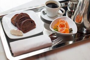 A tray with sliced bread, a cup of coffee, a bowl of fruit, and condiments. - HGU New York Hotel (New York)