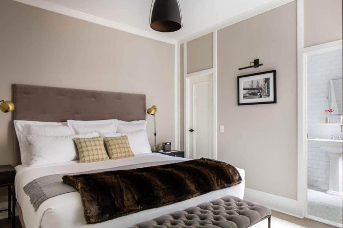 A bedroom with a bed, bedside tables, a lamp, a framed picture, and a door.
