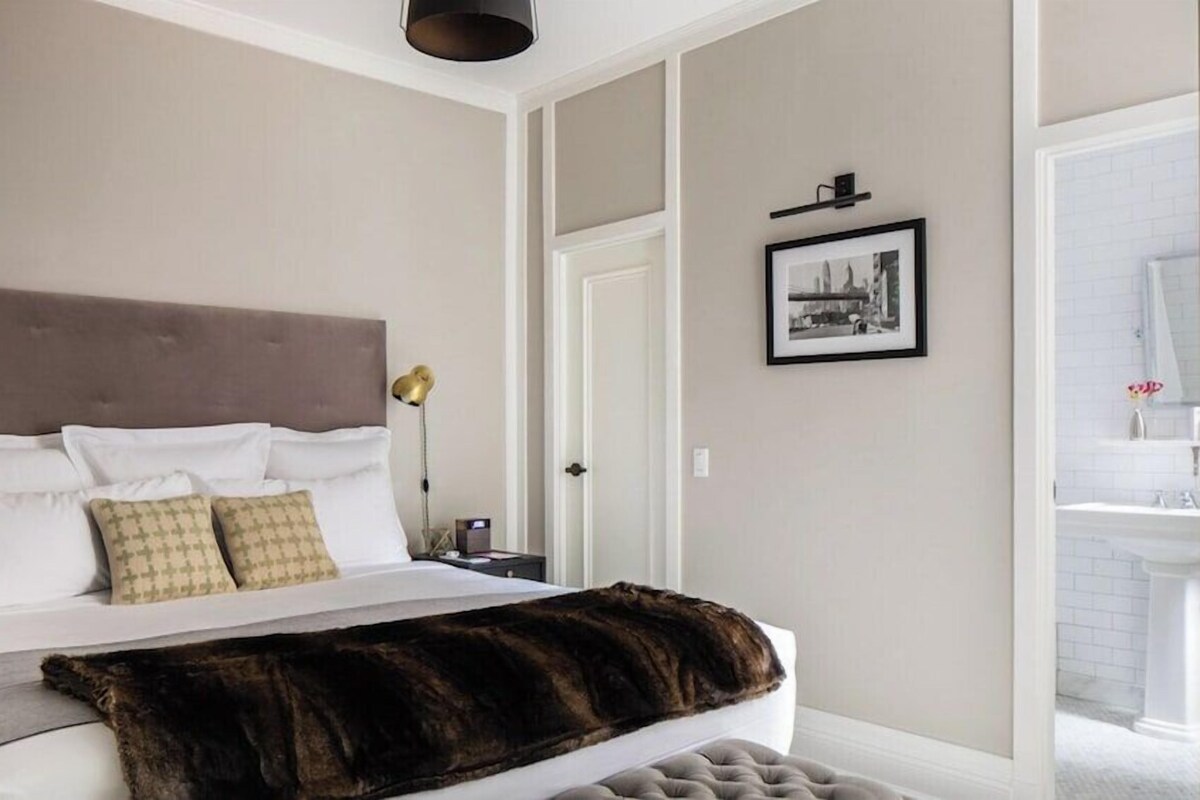 A bedroom with a bed, bedside tables, a nightstand, a framed picture, and a door.