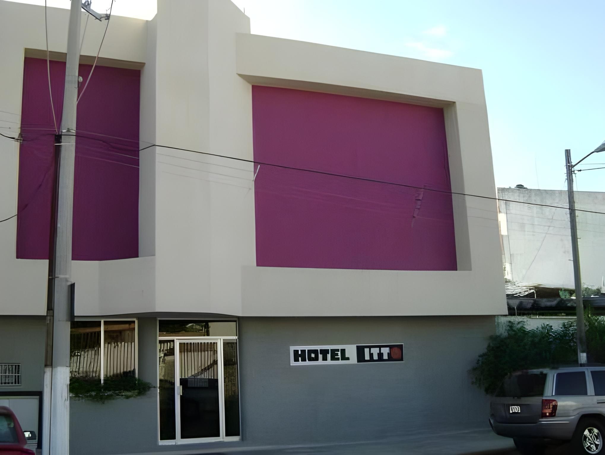 En hotels bygning med et stort skilt, der viser 'HOTEL ITT', og en tydelig indgang med en glasdør.