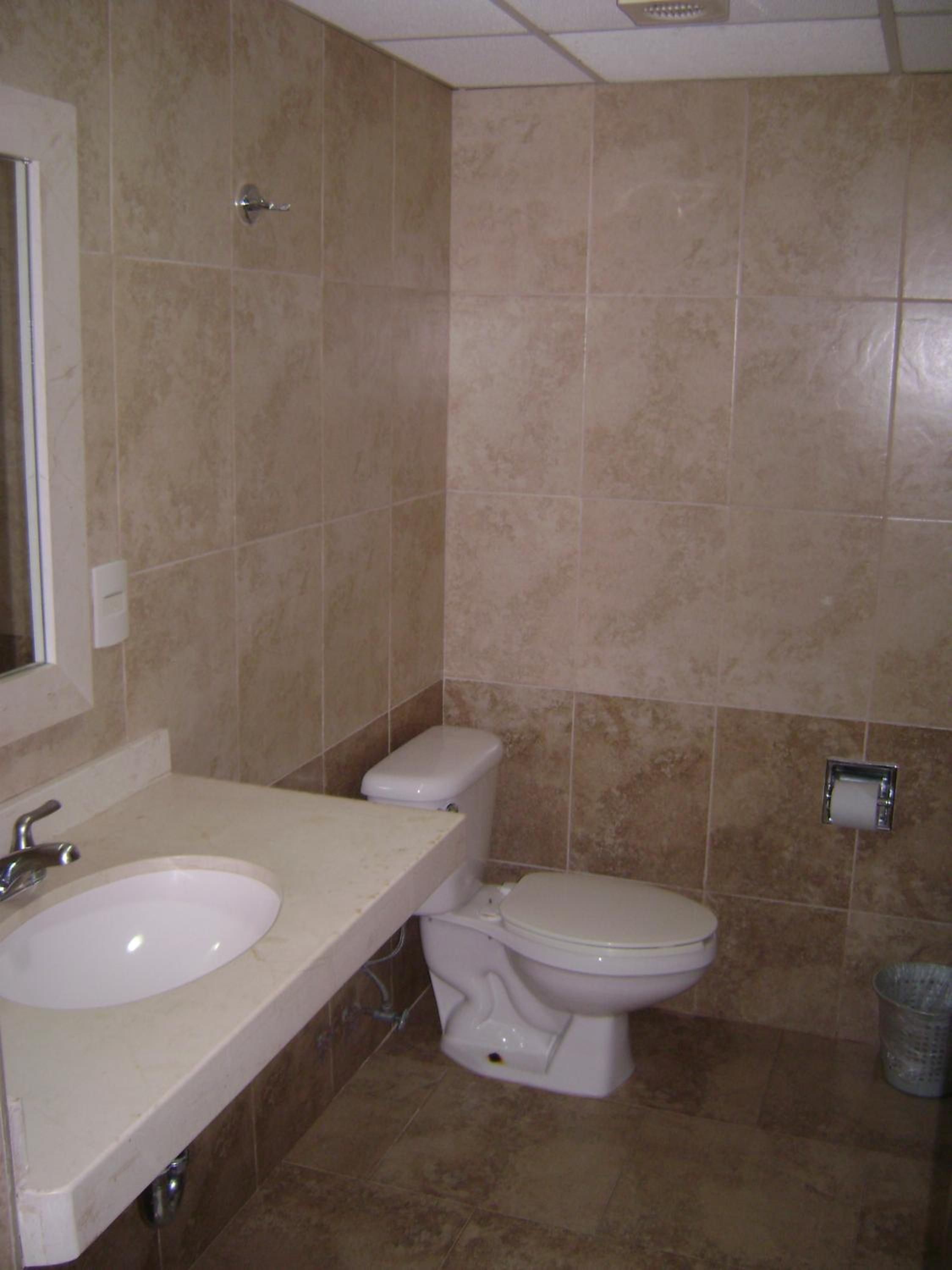 Een badkamer met een wastafel, toilet en een afvalbak.