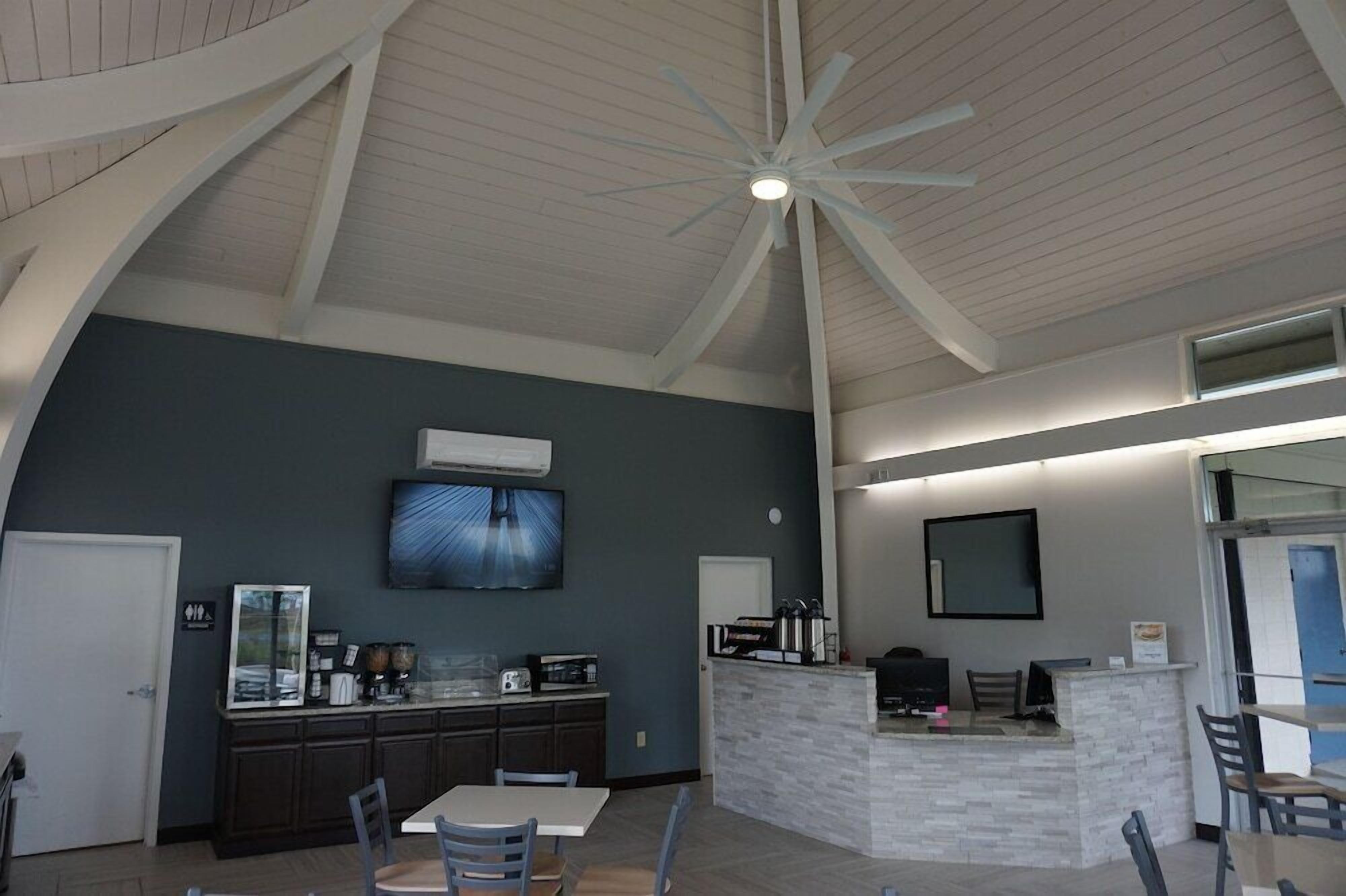 A modern kitchen with a central island, a dining area with chairs, and a ceiling fan.