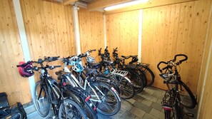 Várias bicicletas estacionadas encostadas a uma parede de madeira em um quarto com piso de azulejos.