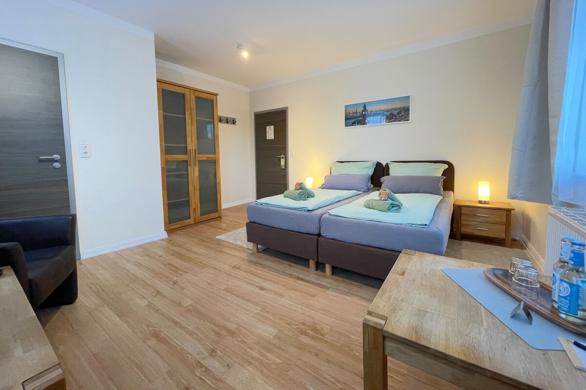 A modern bedroom with a bed, bedside tables, a wardrobe, and a view of a cityscape.
