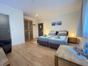 A modern bedroom with a bed, bedside tables, a wardrobe, and a view of a cityscape.