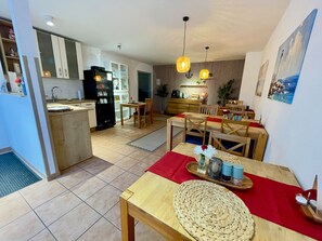 A modern kitchen with a built-in refrigerator, a dining area with wooden furniture, and a kitchen island.