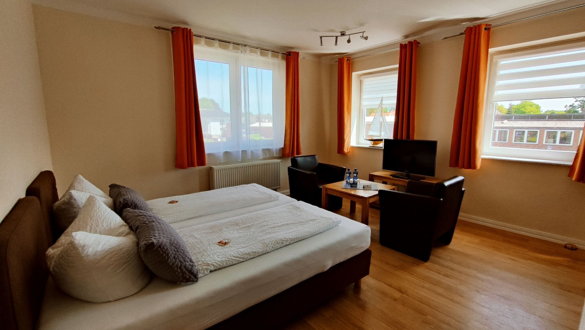 A hotel room with a bed, a desk, a chair, a television, and windows with curtains.