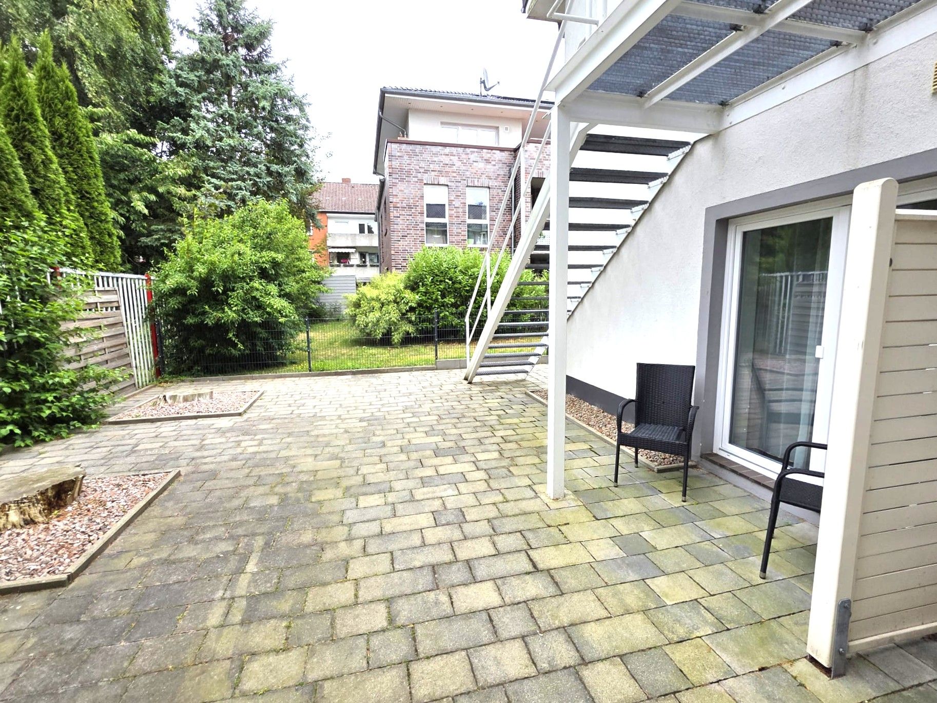 Un patio empedrado con una silla y una escalera que lleva a un edificio.
