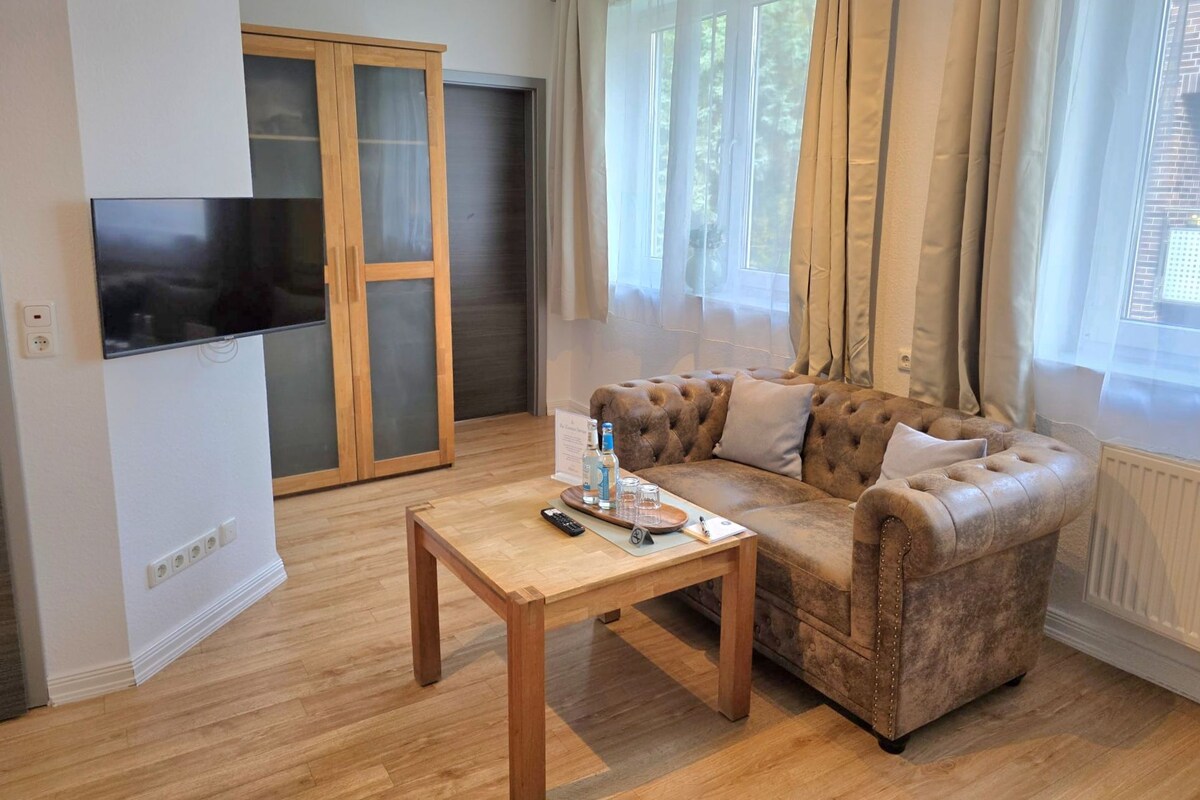 A furnished living room with a sofa, a coffee table, a TV, and a sliding glass door.