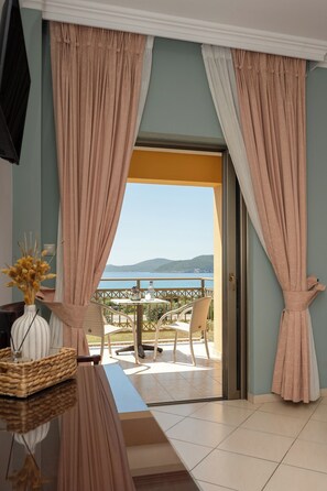 A room with a view of the sea, a balcony with chairs, and a table with a vase and basket. - Finiki Plaza (Pylos-Nestoras)