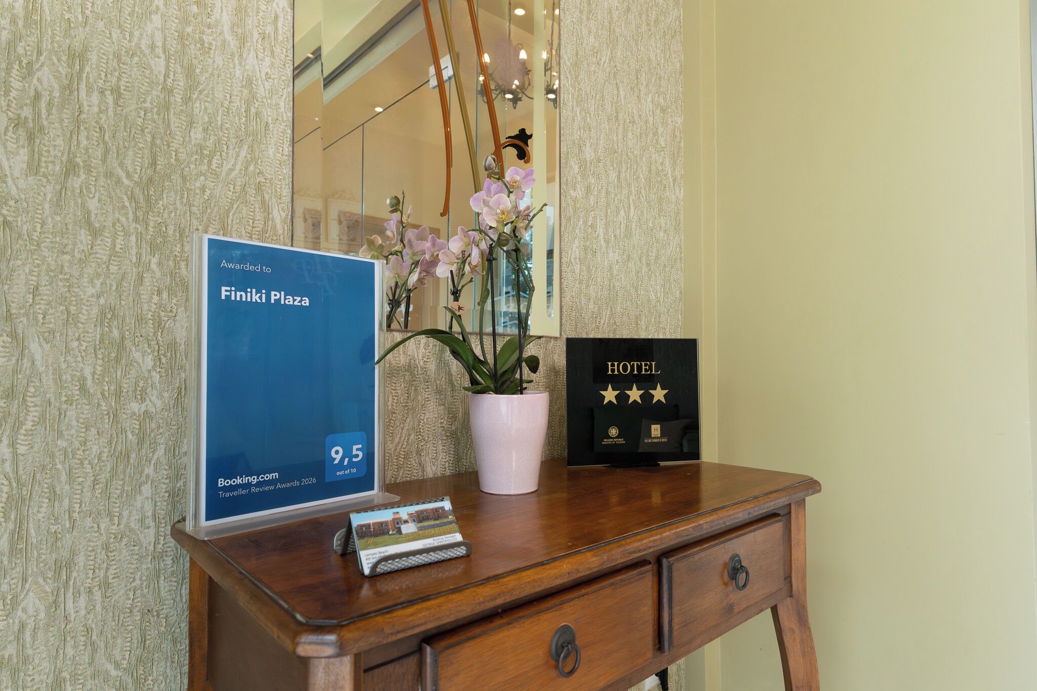 A wooden desk with a framed award, a potted orchid, and a framed certificate.