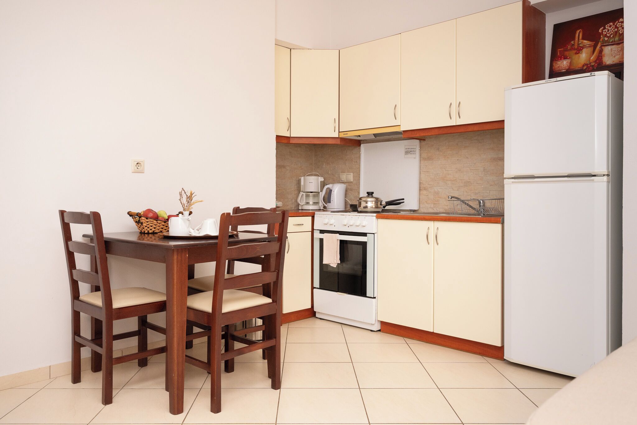 A compact kitchen with a dining table, chairs, a coffee maker, an oven, and a refrigerator.