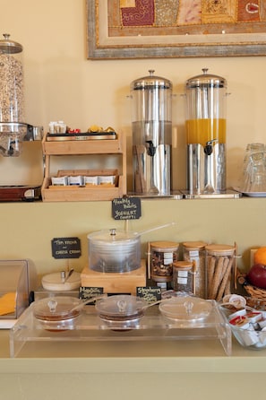 Zona de buffet con diferentes recipientes y etiquetas de comida, incluyendo yogur, café y cereales.