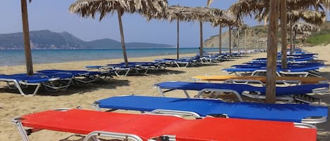 Vlak bij het strand, ligstoelen aan het strand, parasols, een strandbar