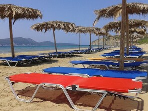 Playa en los alrededores, camastros, sombrillas y bar en la playa 