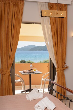 Habitación de hotel con cama, una mesa con desayuno, una silla y vista al mar.