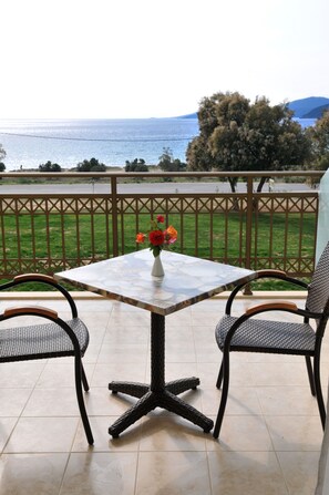 A patio with a table and two chairs, a vase with flowers, and a view of the sea. - Finiki Plaza (Pylos-Nestoras)