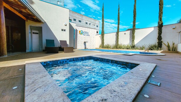 Un área de spa con un jacuzzi, una piscina y un edificio con un cartel que dice "Recanto das Caldas".