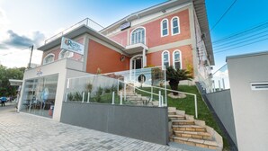 Un hotel de fachada roja, entrada de cristal y una escalera que lleva a la entrada.