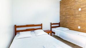 Una habitación de hotel con dos camas individuales, cabeceros de madera, ropa de cama blanca y una pared decorativa de madera.