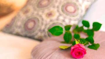 A bed with a pink pillow and a rose.