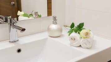 A white bathroom sink with a chrome faucet, a soap dispenser, and a towel with a rose.